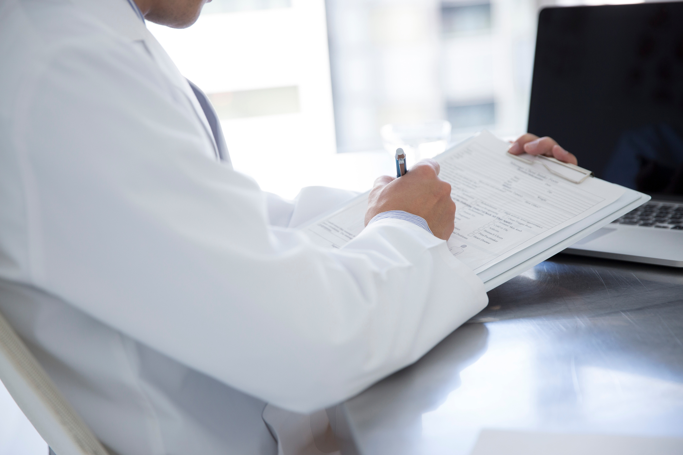 Doctor writing medical record with reference to meeting materials